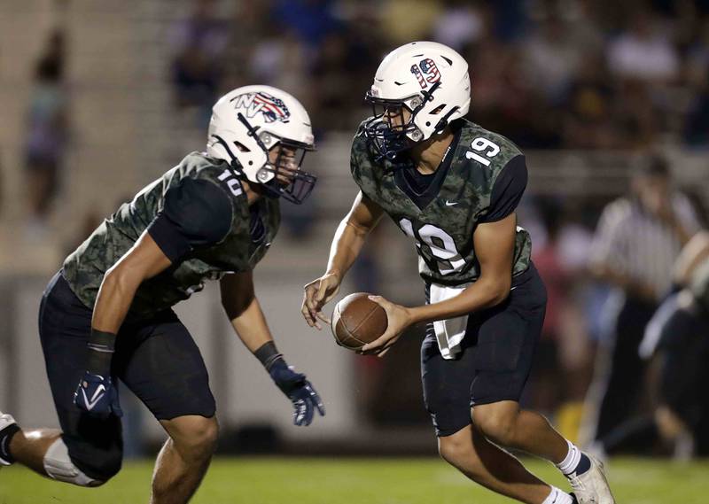 Neuqua Valley's Ryan Mohler (19) hands the ball to Neuqua Valley's Trevor Torres (10) Friday September 16, 2022 at Barbara J. Barrows Stadium in Naperville.