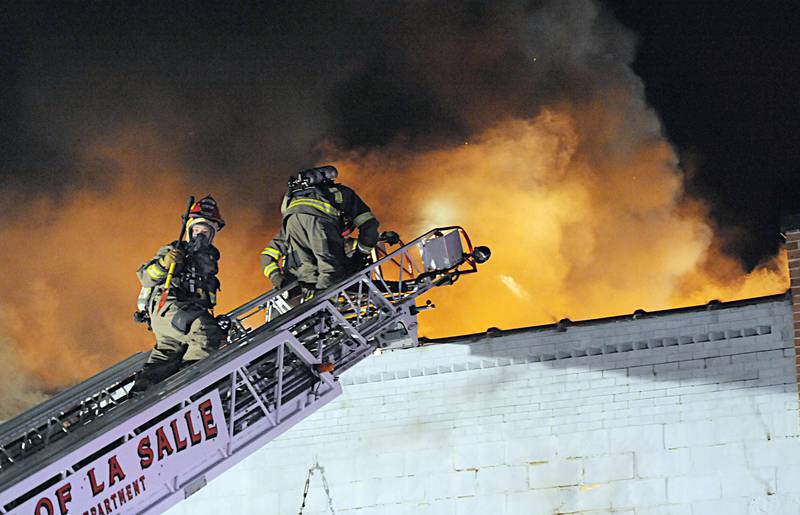 Firefighters battle flames above apartment outside Skoogs Pub & Grill on Sunday, May 10, 2015 downtown Utica.