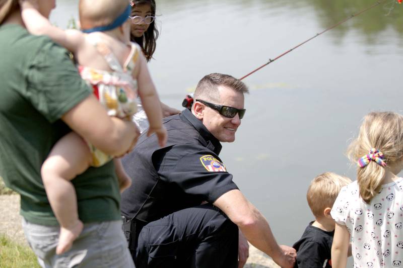 Wheaton Police Officer Brian Gabryel assists young anglers during the Wheaton Police Department and DuPage County Forest Preserve Police Cops & Bobbers community fishing event at Herrick Lake Forest Preserve in Wheaton on Wednesday, June 7, 2023.