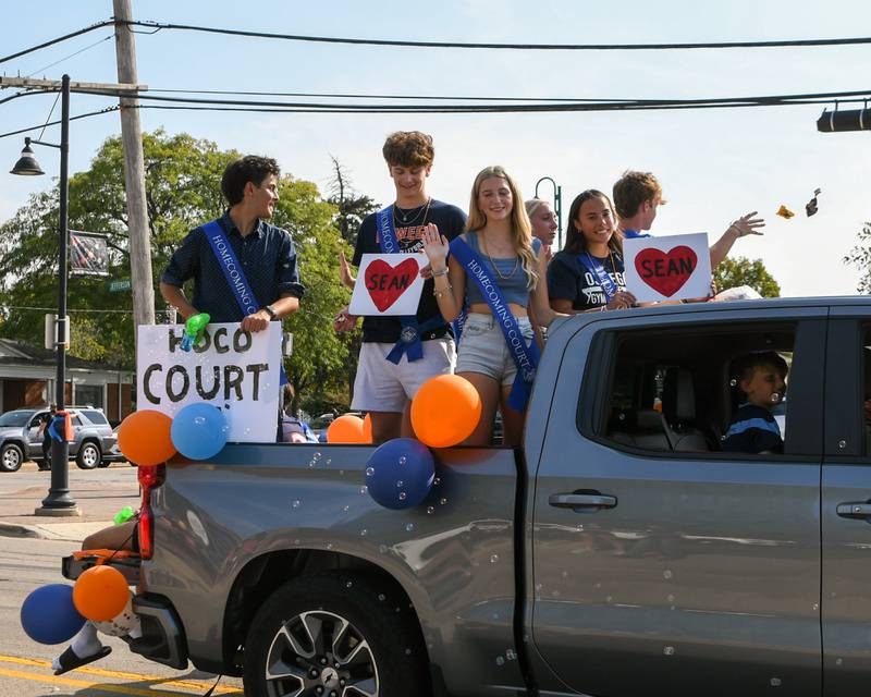 Oswego High School homecoming court takes part in the homecoming parade through downtown Oswego on Sunday Sept. 15, 2024, and hold signs with a heart with the word Sean to honor him. Sean lost his life in a car crash.