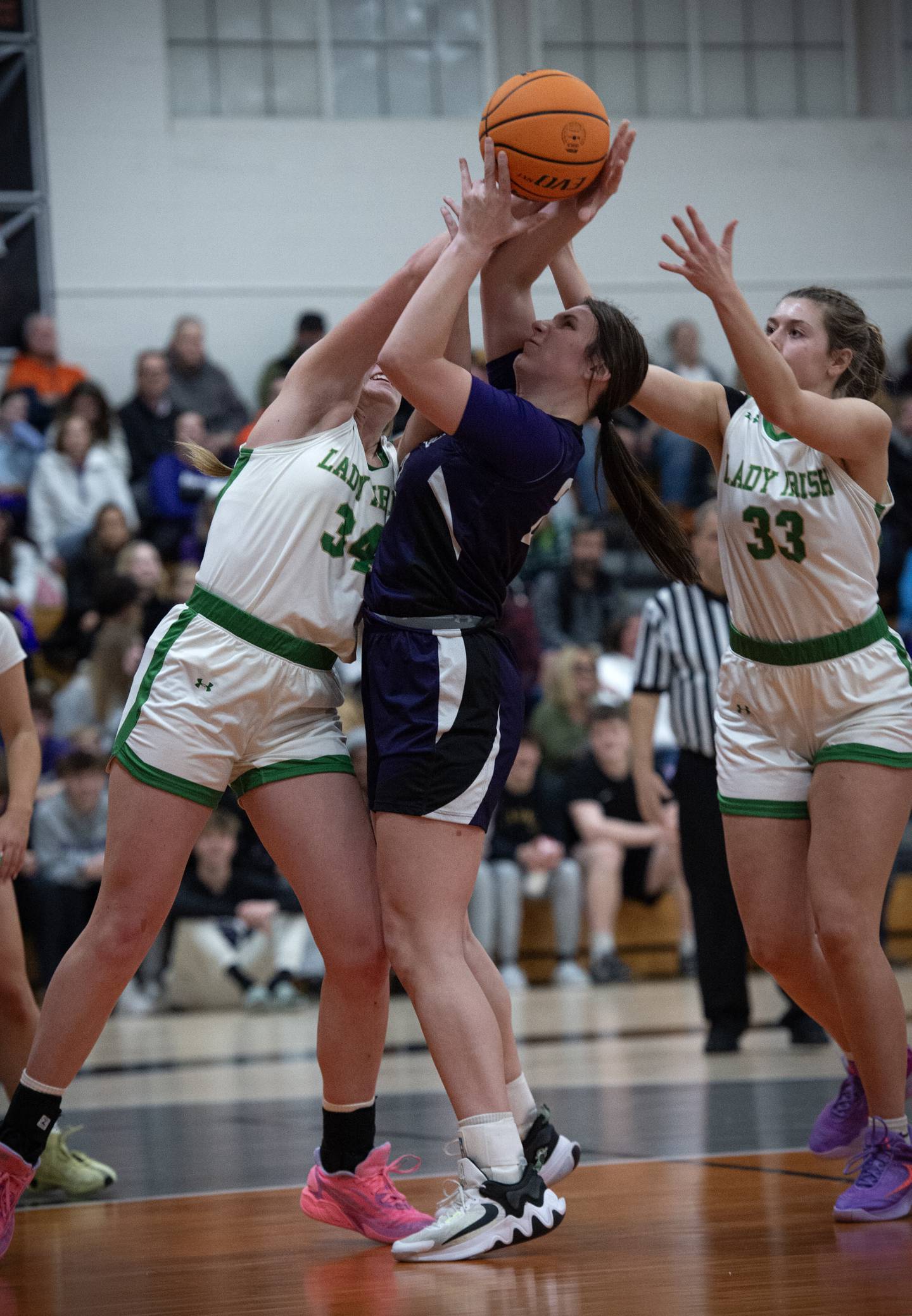 Manteno's Maddie Gesky, center, brings in a rebound over Seneca's Tessa Krull, left, and Audry McNabb, right, during the IHSA Class 2A Beecher regional championship Friday, Feb. 21, 2025.