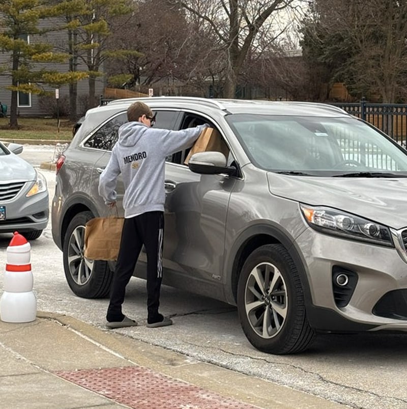 A volunteer hands out gift bags filled with food and holiday treats to seniors during the Cary Park District's Holiday Party in a Bag program on Dec. 22, 2025.
