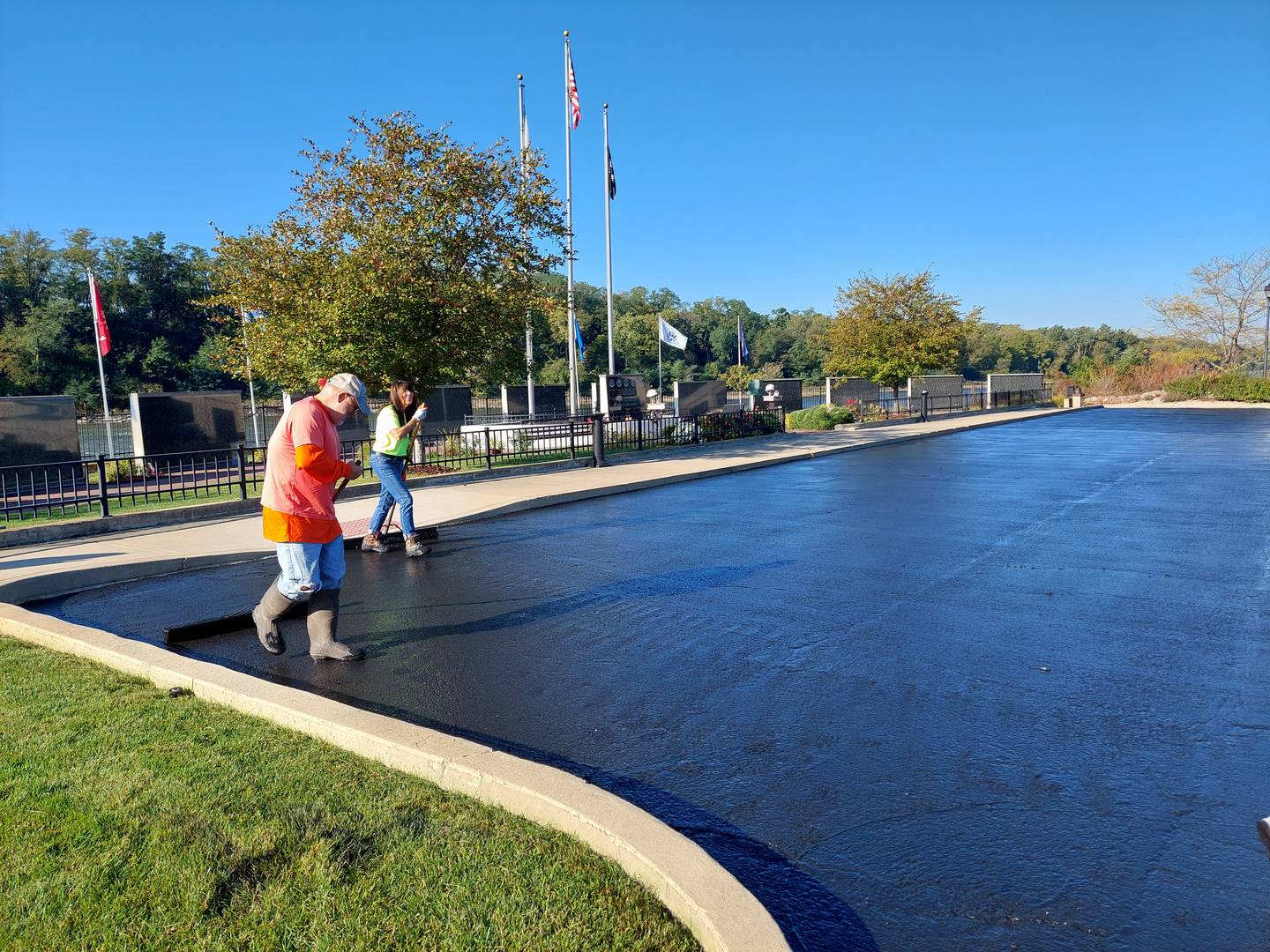 (From left) David Raikes, of Laborers Local 393 in Marseilles, and Corinne Tomaseski, of Ski Seal Coating and Maintenance in La Salle, volunteer their time Tuesday, Oct. 3, 2023, resurfacing the parking lot at the Middle East Conflicts Wall in Marseilles.