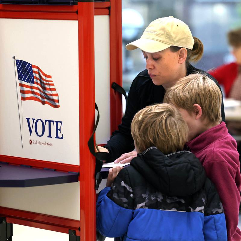 Kay Aldrich, from DeKalb, shows her kids Oliver Eich, (left) 6, and Elliott Eich, 7, the voting process Tuesday, Nov. 5, 2024, as she casts her ballot on Election Day at the DeKalb Public Library.