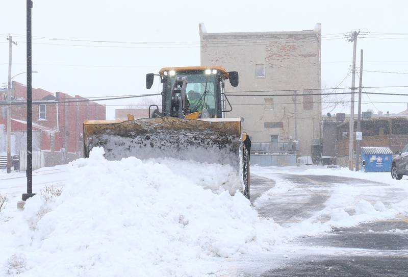 An excavator piles snow in the parking lot near the intersection of Marquette and Pleasant Street on Monday, March 16, 2026 in Princeton.