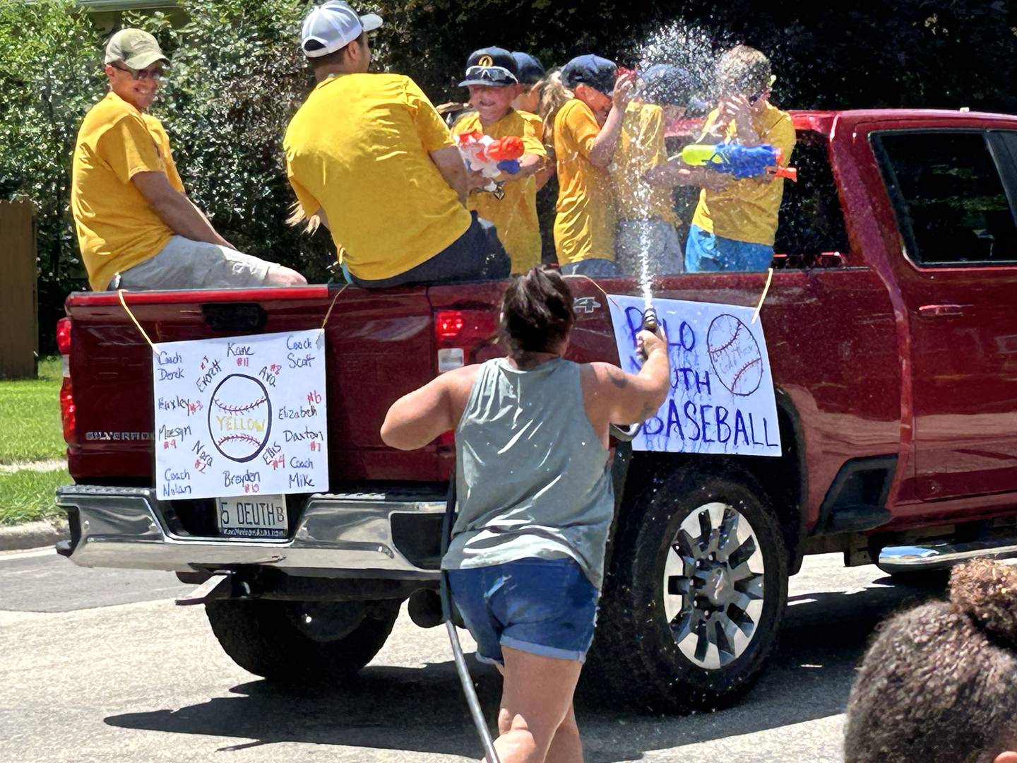 Billie Quaco has a water fight with one of the youth baseball teams as the team cruises past her home during the Town & Country Days Parade on Sunday, June 29, 2025.