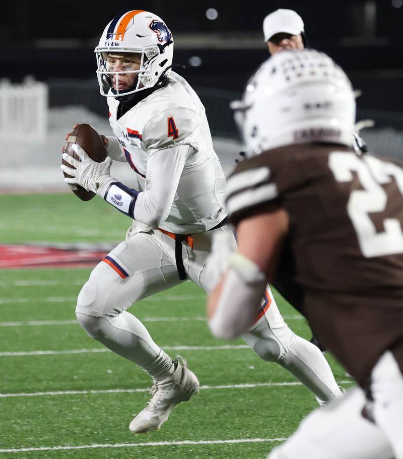 Oswego's Drew Kleinhans rolls away from the Mount Carmel pass rush Wednesday, Dec. 3, 2025, during their IHSA Class 8A state chamionship game in Huskie Stadium at Northern Illinois University in DeKalb.