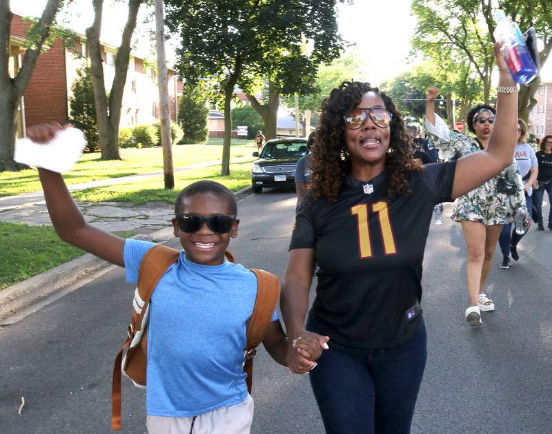 Jeremiah Holley, 10, and his mom Janeta Allen, from DeKalb, chant as they march Friday, July 18, 2025, during the DeKalb Peace Walk and Rally. The event, which featured a march, food vendors and music, was held to encourage the community to work together against gun violence.