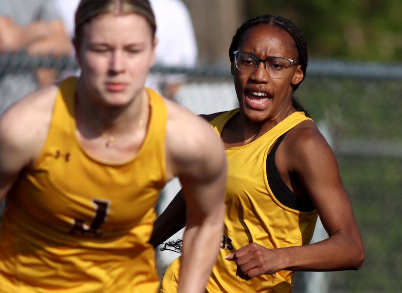 Jacobs’ Aaliyah Guichon, right, approaches teammate Layla Merlin in the 400-meter-relay during the McHenry County Track and Field Meet at McCracken Field on Thursday, April 24, 2025, in McHenry