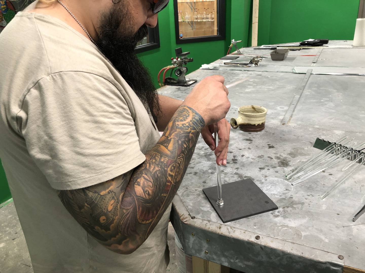 Joshua Patterson practices flattening a molten glass into a pendant at Otto’s in McHenry on July 18, 2022.