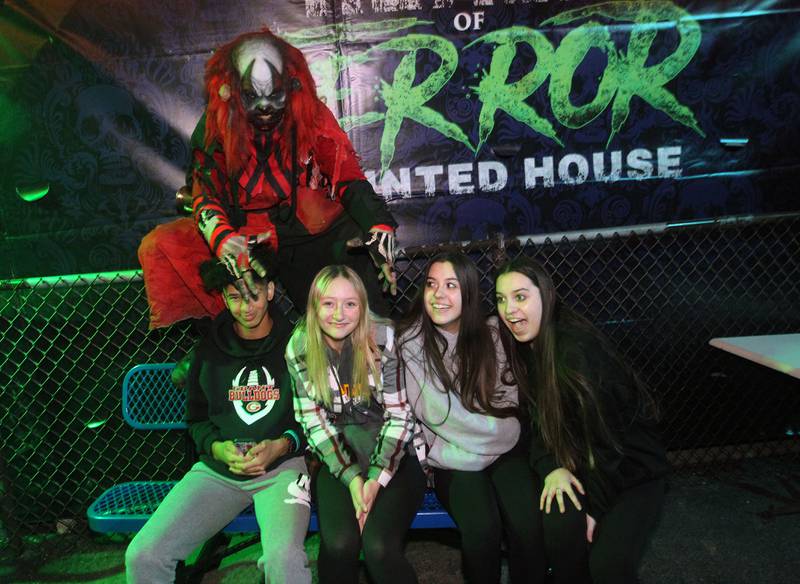 Dozer the Clown (Martin Nelson) sits with Cameron Houghon, of Round Lake, Ella Franck, Maya Colon and her twin sister, Mariah, all of Wauconda while waiting to get into the Realm of Terror Haunted House in Round Lake Beach.