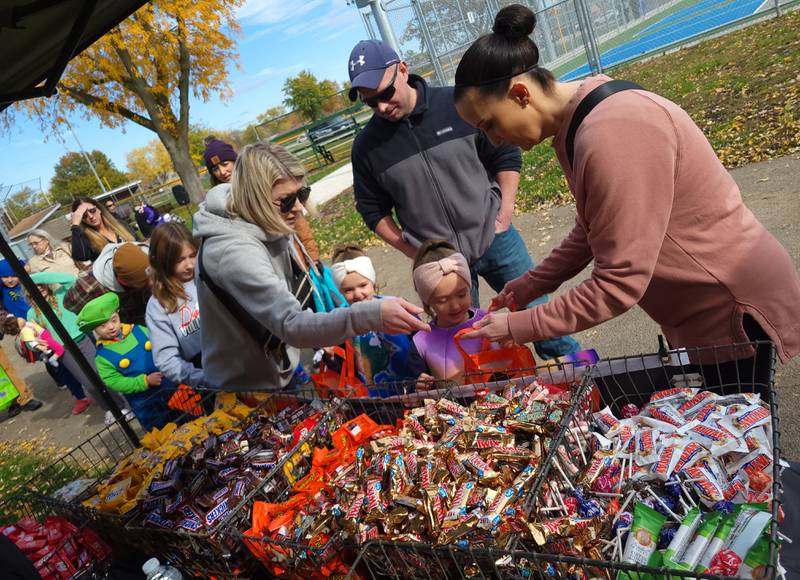 Twins Addy and Ensley Smith, 5, of Peru are helped by mom Crystal (left) and aunt Charity Howard (right) with choices from a wide variety of candy treats available at Peru's Halloween Celebration at Washington Park.