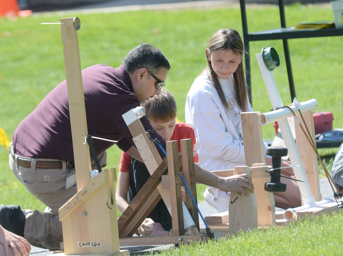Oregon sixth grade teacher Aaron Mendoza helps one of his students set up their catapult on Friday, May 9, 2025 on the lawn behind the Oregon Elementary School.