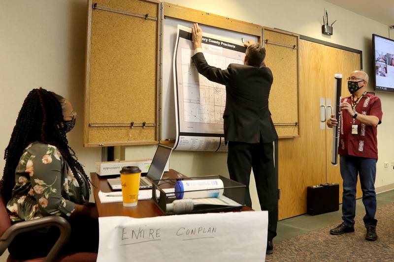 McHenry County Deputy County Administrator Scott Hartman hangs a county voting district map for board member Carlos Acosta, right, during a McHenry County Administrative Services Committee meeting on Wednesday, May 5, 2021, in Woodstock.