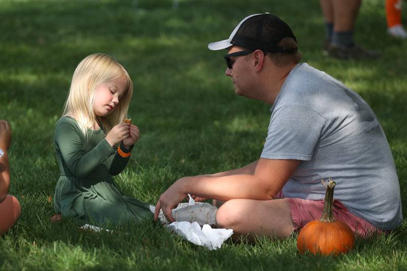 Avery, 3-years old, her father Brad Roe find shade to eat lunch at the Autumn Family Fun Fest on Saturday, Sept. 23, 2023 in Plainfield.