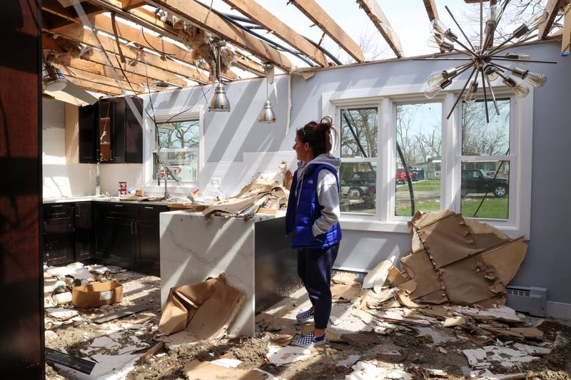 Emily LaVoie steps over debris in what was the kitchen at her Elmwood Drive home in Aroma Township on April 8, 2026. She and her husband, Dave Herberger,  are in the process of planning repairs for the damage caused by the EF-3 tornado about one month ago.
