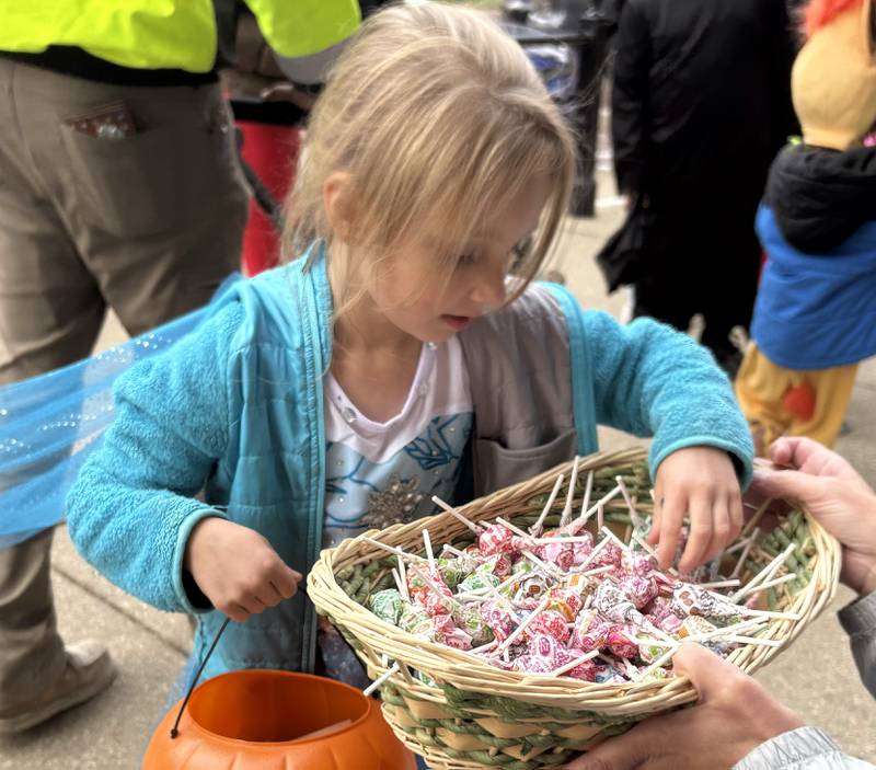 Kayleigh Prudhomme, 5, of Woodstock grabs a piece of candy at Anime and Things during Halloween on the Square in Woodstock Oct. 31, 2025.