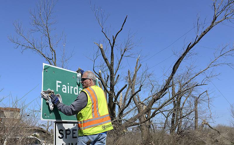 IDOT worker Bob Ott  repairs the sign for the town after damage on Friday, April 10, 2015, following a tornado that hit the town of Fairdale, Ill., Thursday night.  The National Weather Service says at least two tornadoes churned through six north-central Illinois counties. (AP Photo/Matt Marton)