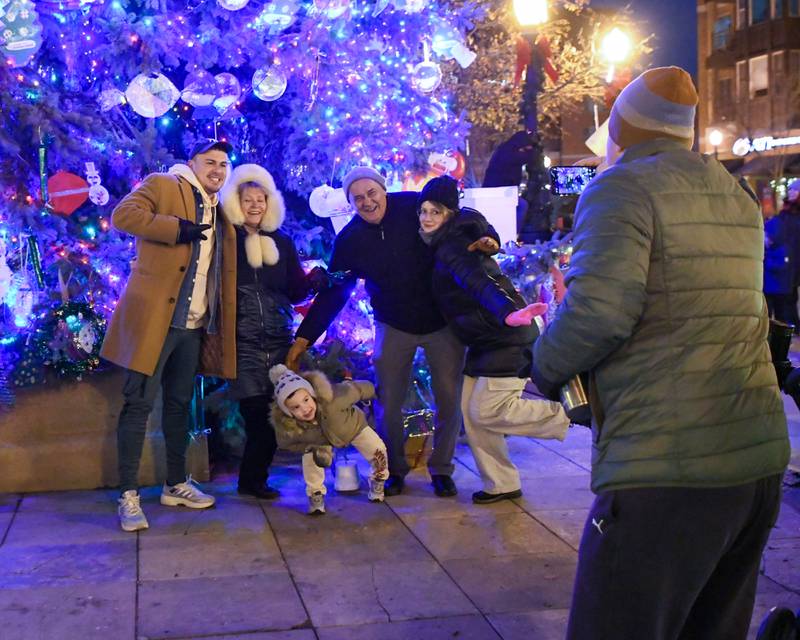 Mihai Partac of Downers Grove takes a picture of friends from New York Randoph Cardenas, Natalia Levanovich, Ksenia Cardenas, Christian Cardenas, 4, and Konstantin Cosgulins on Friday Nov. 29, 2024, after the Christmas tree lighting ceremony held in downtown Downers Grove.