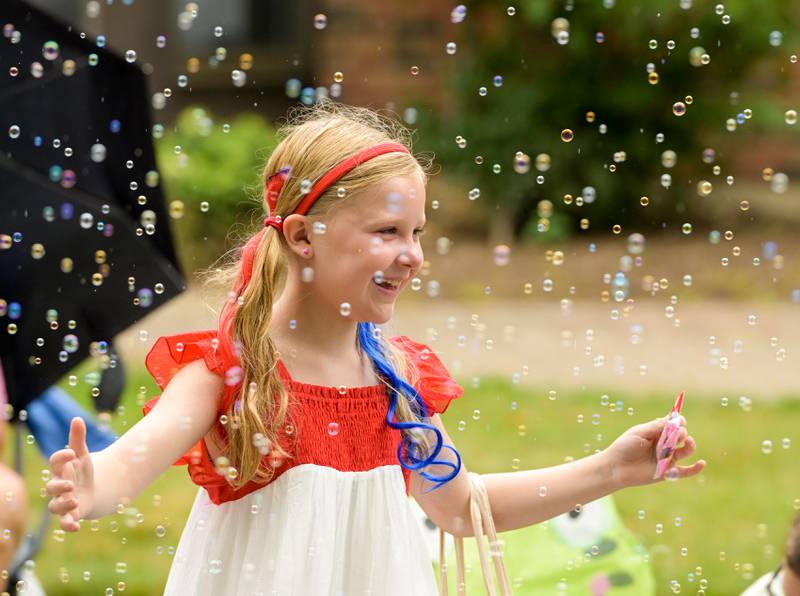 Grace Gerlach, 8 of Wheaton twirls around floating bubbles as she and her family attend the annual Wheaton Independence Day Parade on Thursday, July 4, 2024.