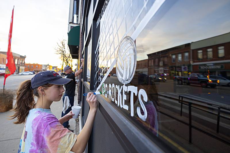 Maya Kobbeman adds some color to the window of Barcode in downtown Rock Falls in support of the volleyball team Monday, Nov. 6, 2023.