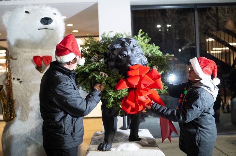 Dionisio Franquiz Perez, 11, of Kankakee, right, assists Kankakee Mayor Chris Curtis placing the holiday wreaths on the lion statues outside the Kankakee Library on Thursday, December 4, 2025.