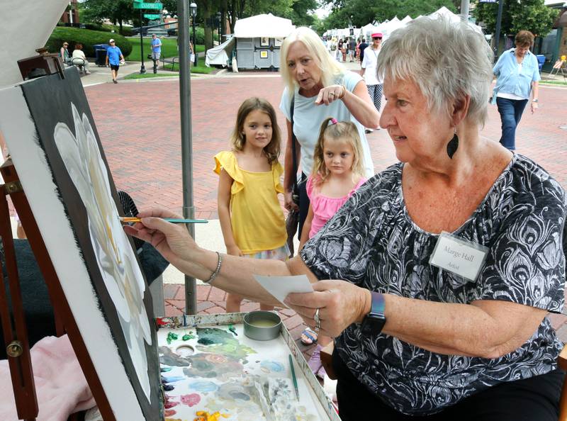 Marge Hall, of Winfield, draws some spectators as she works on her oil painting Saturday, July 26, 2025, during the Geneva Arts Fair in downtown Geneva.