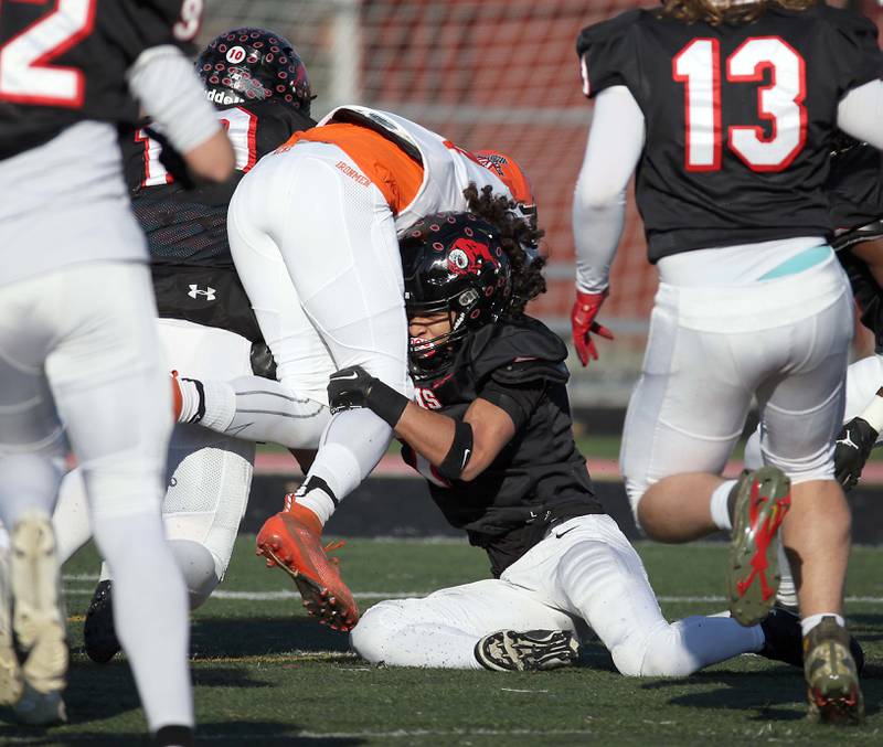 Glenbard East's Stevyn Fox (7) wraps up a Normal player during the IHSA Class 7A quarterfinals Saturday November 11, 2023 in Lombard.