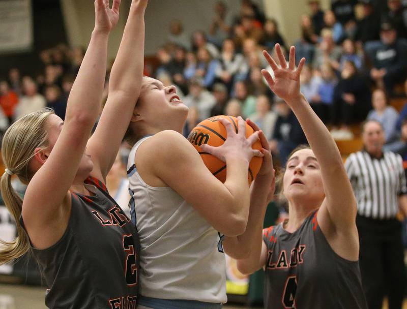 Cissna Park's Emma Malabahar tucks the ball in as she fights in the lane while Flanagan-Cornell/Woodland's Kora Edens and Aubry Edens defend during the Class 1A Sectional semifinal game on Tuesday, Feb. 25, 2025 at Midland HIgh School.