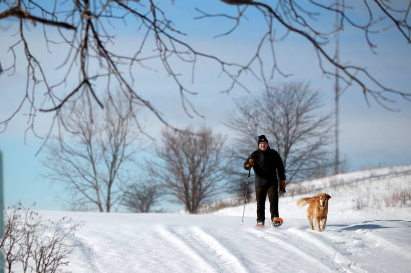 Ted Welch, who is visiting family from Maine, and his dog, Mac, walks with snowshoes at Settler’s Ridge in Geneva on Saturday, Jan. 13, 2024.