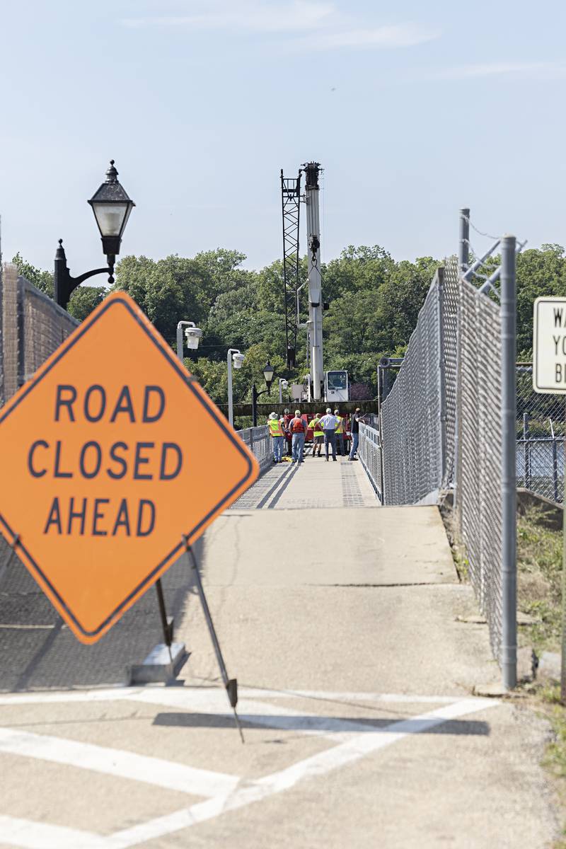 Workers perform maintenance on the upper dam Wednesday, July 19, 2023. For at least the next three days the pedestrian bridge crossing the dam will be closed for maintenance.