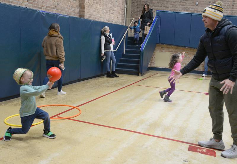 Brendan Gilliam and his dad Frank play baseball in the Downers Grove Community Center during the Downers Grove Bunny Hop Egg Hunt Friday, March 22, 2024.