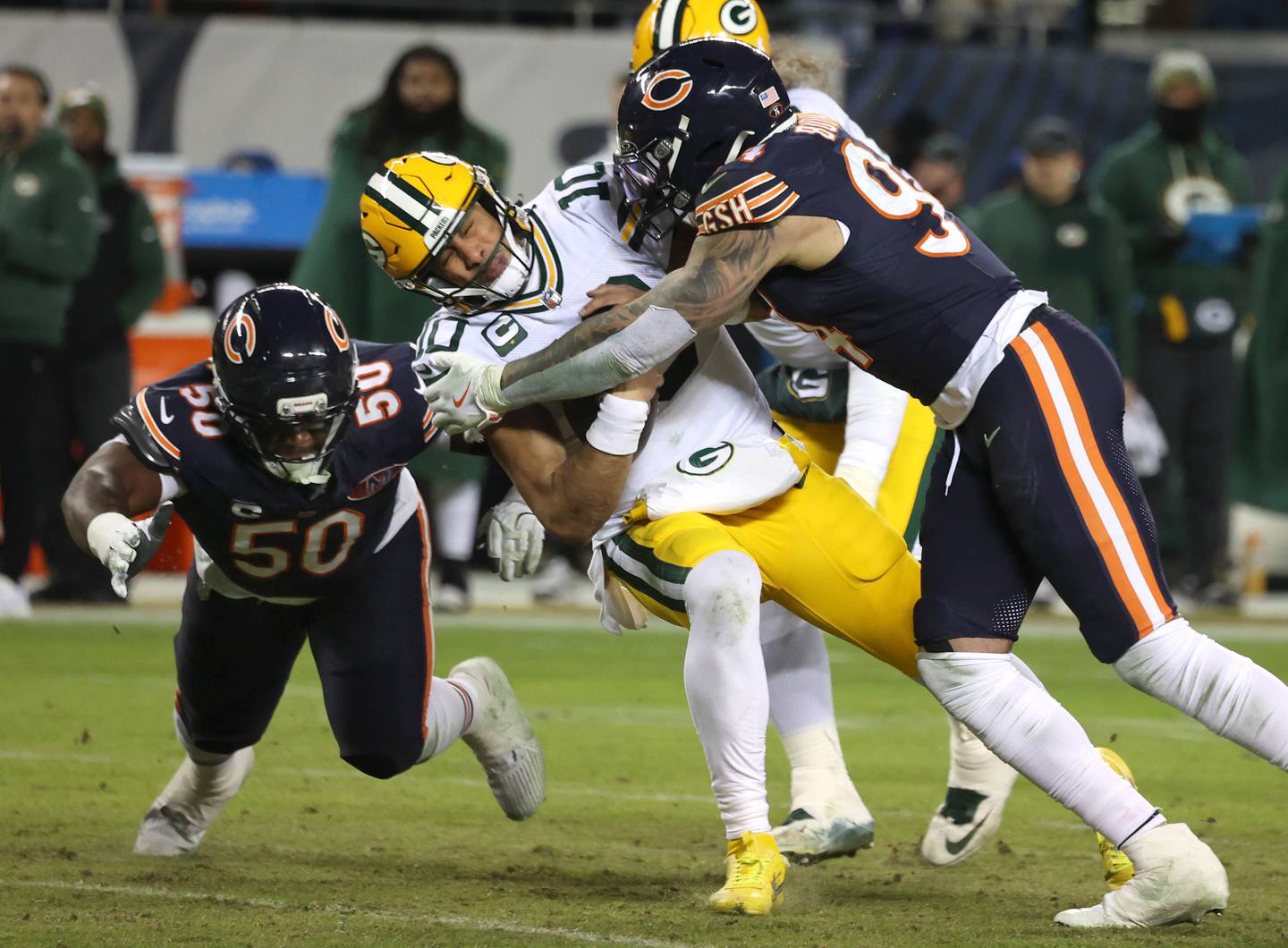 Chicago Bears defensive end Austin Booker (right) and defensive end Grady Jarrett bring down Green Bay Packers quarterback Jordan Love during their NFL Wild Card game Saturday, Jan. 10, 2026, at Soldier Field in Chicago.