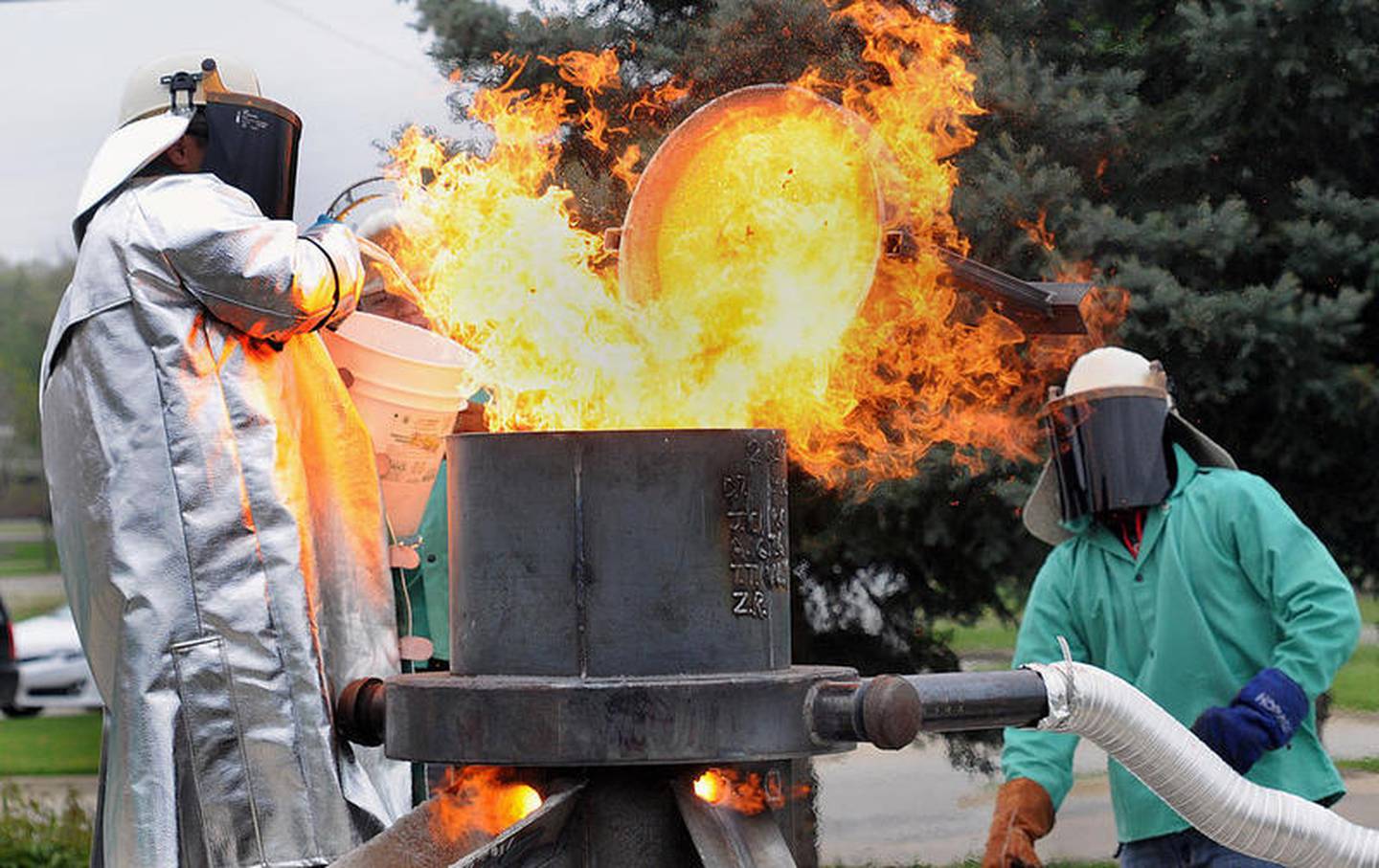 A Streator High School welding student pours coke, which is refined coal used as fuel, into a furnace in an attempt to melt iron as instructor David Taylor looks on during an iron pour demonstration earlier this week.