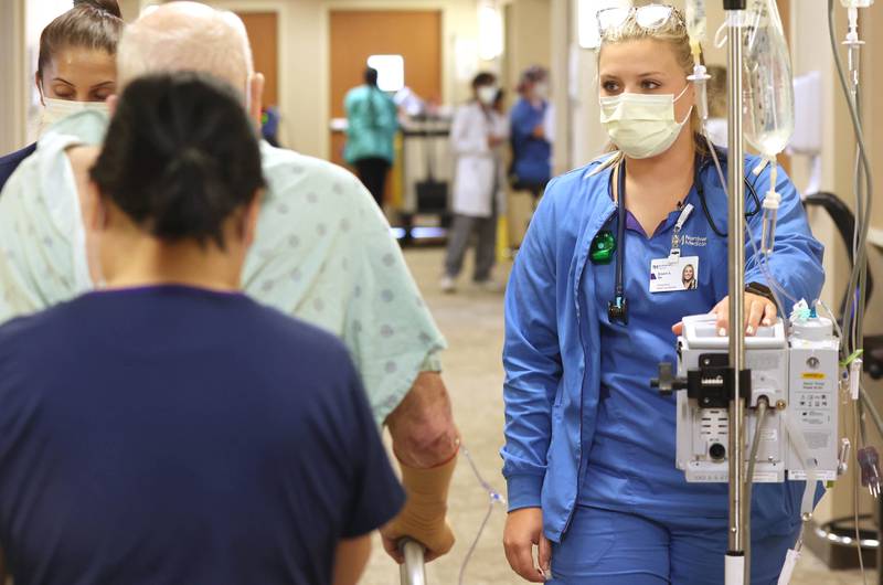 Breann Aubry, registered nurse, pulls the IV stand as she walks with a patient Tuesday, July 26, 2022, at Northwestern Medicine Kishwaukee Hospital in DeKalb.