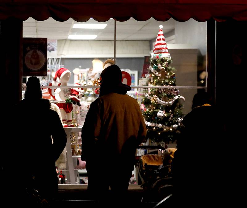 People window shop during the Lighting of the Square Friday, Nov. 24, 2023, in Woodstock. The annual holiday season event featured brass music, caroling, free doughnuts and cider, food trucks, festive selfie stations and shopping.
