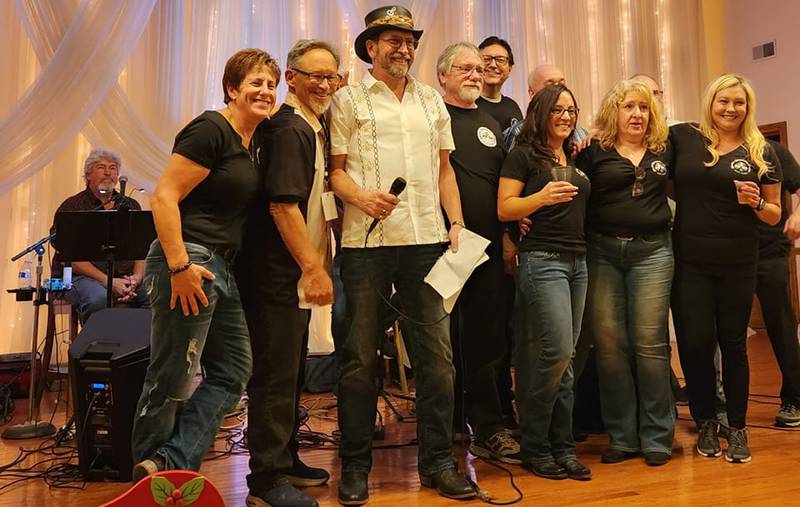 Tom Grotovsky (center, holding microphone), owner of Great American Bagel in Joliet, stands with other organizers of the annual Brats Bourbon, and Brews". This year's event will be held Aug. 23 at the Jacob Henry Mansion in Joliet. Proceeds will help provide five service dogs for five Illinois veterans.