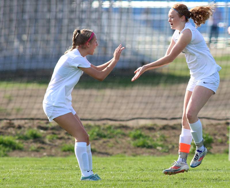 Woodstock’s Keira Bogott, right, celebrates the Blue Streaks’ first goal with Madeline Day in varsity soccer on Wednesday, April 23, 2025, at Johnsburg High School in Johnsburg.