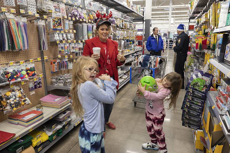 Sister Sophia (left), 7, and Alayna Richards, 5, celebrate chosen gifts in the arts and crafts aisle Saturday, Dec. 10, 2022 at the Sterling Walmart. Amanda Mohr, wife of officer Jeff Mohr helped the two young ladies pick out the gift items.