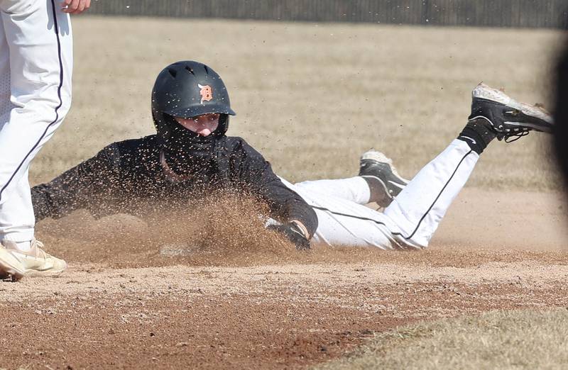 DeKalb’s Landon Simonson slides safely into second after walking on a wild pitch and hustling for an extra base during their game against Dixon Tuesday, March 28, 2023, at DeKalb High School.