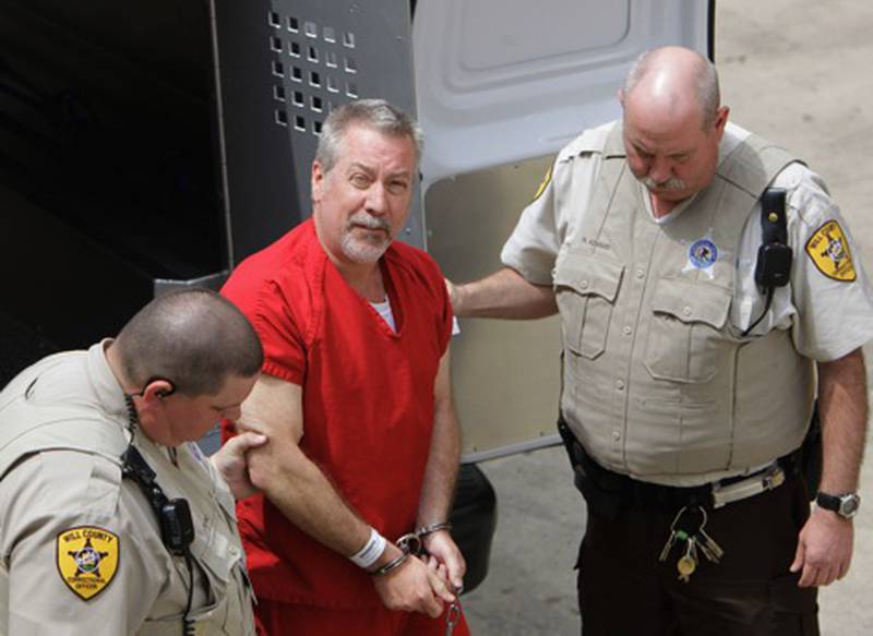 In this May 8, 2009 file photo, former Bolingbrook, Ill, police sergeant Drew Peterson, center, arrives at the Will County Courthouse in Joliet, Ill. On Monday, May 18, 2009, Peterson is scheduled to be arraigned on first-degree murder charges in the 2004 drowning death of his third wife Kathleen Savio.