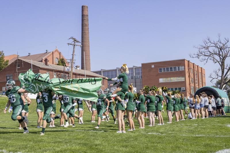 Members of the St. Bede Bruins tear through the homecoming banner at the start of their home game against the Elmwood Park Tigers on September 30, 2023