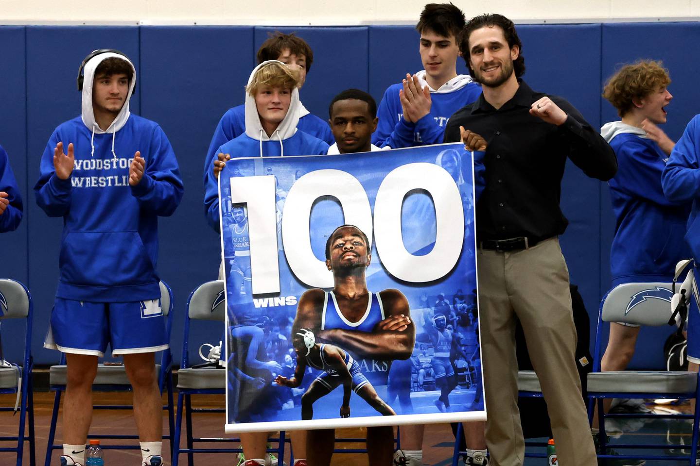 Woodstock's Taqi Baker, pictured with coach Matt Kitsis and his Blue Streaks teammates celebrates his 100th career victory.