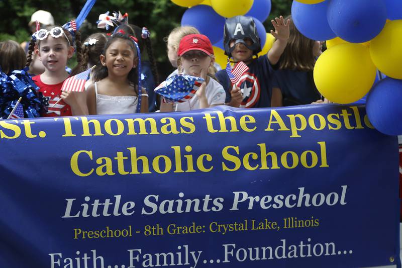 Children wave as they ride on the St. Thomas the Apostle Catholic Church and Little Saints Preschool foal on Sunday, July 7, 2024, during Crystal Lake’s annual Independence Day Parade on Dole Avenue in Crystal Lake. This year’s parade feature close to 100 units.