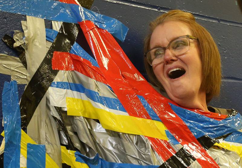 Mrs. Lori Atilano administrative assisant reacts after being duct taped to a wall during the "Tape The Teacher" fundraiser on Friday, March 20, 2026 at Logan Jr. High School in Princeton.