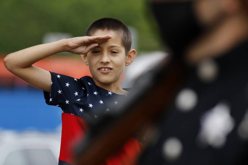 Gabriel Garcia of Crystal Lake, 10, salutes the flag as members of the honor guard march past during the Memorial Day parade on Monday, May 31, 2021 in Crystal Lake. The parade began at Crystal Lake Central High School and continued through downtown, ending at Union Cemetery with a ceremony.