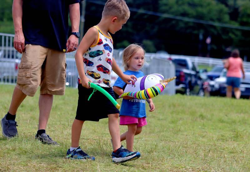 Oaklynn Bankert, 3, of Fox Lake strolls with her brother Aspen, 6, and their treasures from the carnival during Fiesta Days at Petersen Park in McHenry Sunday.