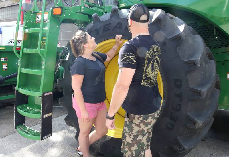 Kailey Adam, from Denver Col., and Jimmy Wright, from Gilberts, check out the tire of a combine in the agricultural area the first night of Corn Fest Friday, Aug. 26, 2022, in DeKalb.
