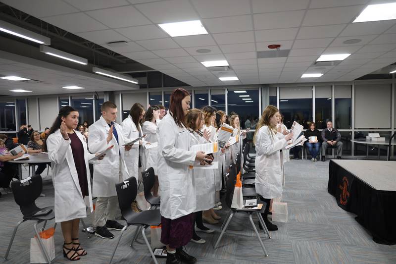 After receiving their white coats as part of a ceremony Monday, March 14, 2022, McHenry High School students take the Hippocratic Oath. About two dozen students were honored in the white coat ceremony after they completed four years of the high school's medical program.