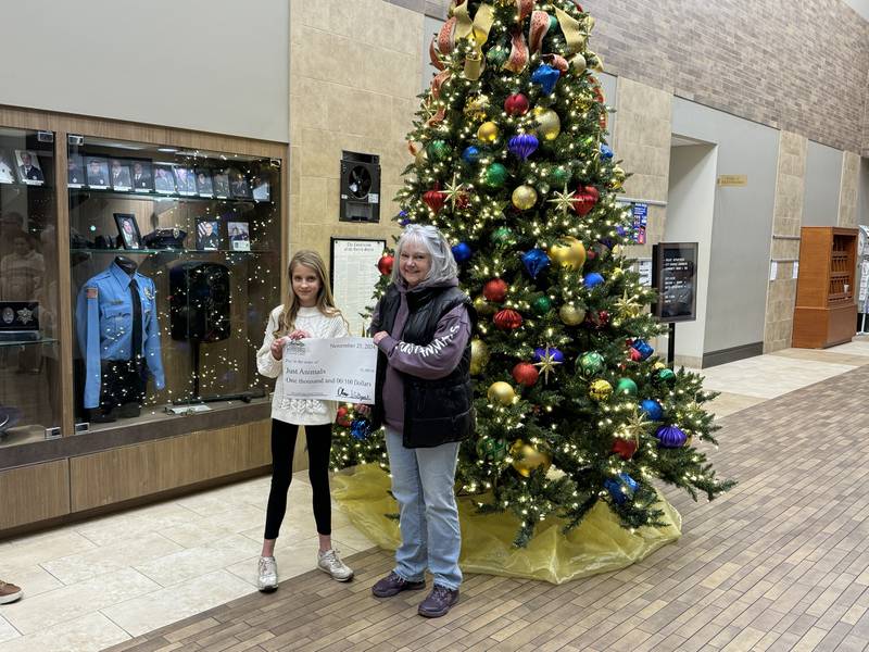Clare W. from Immaculate Conception School hands Brenda Leake of Just Animals in Mazon a check for $1,000.